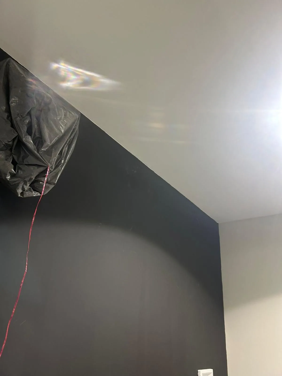 Ligne nette entre mur foncé et plafond blanc avec équipements protégés
